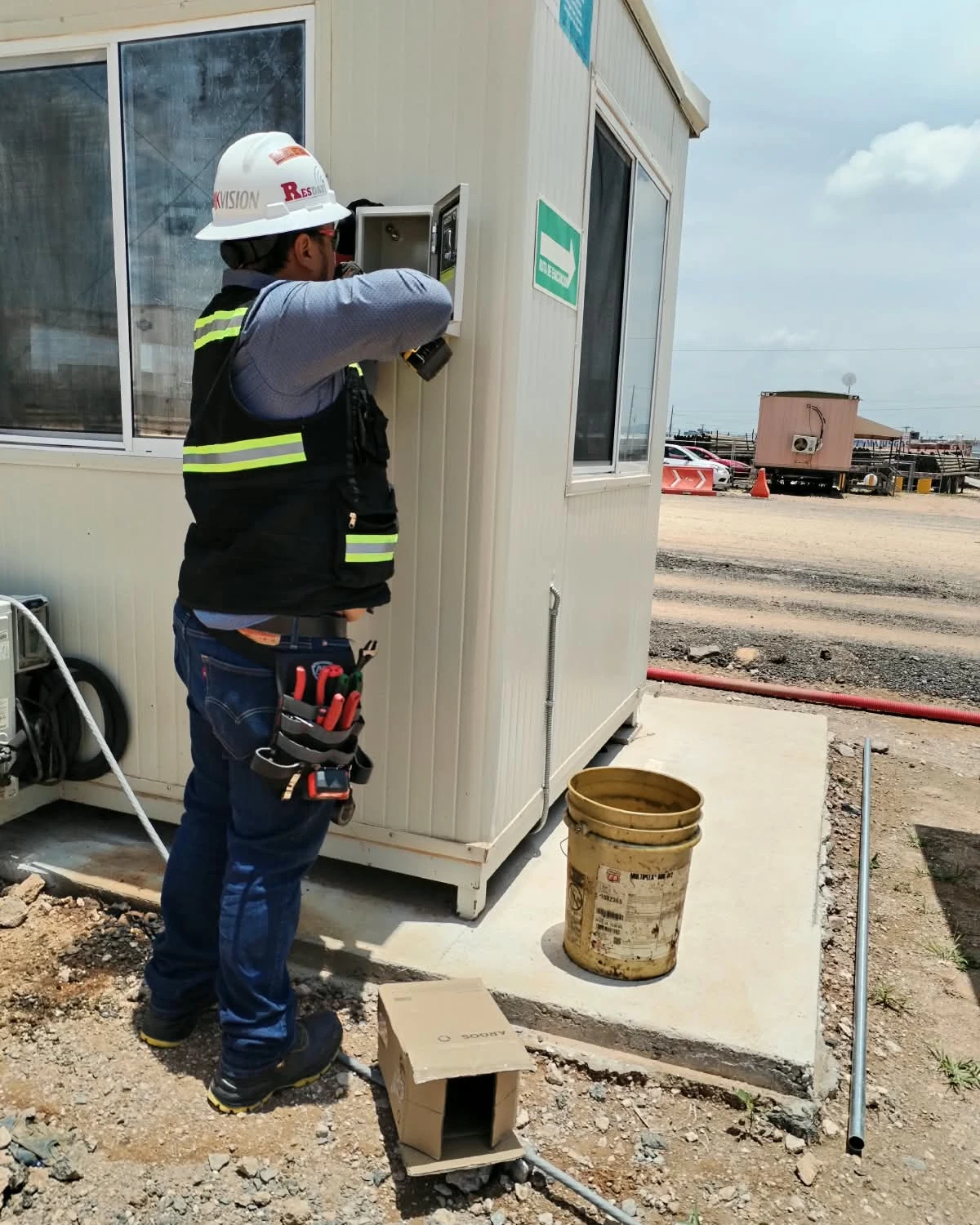 Técnico instalando un gabinete eléctrico en una caseta de obra
